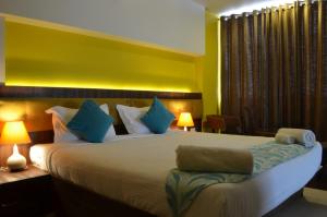 a bedroom with a large bed with blue pillows at Luxtay Suites in Bangalore