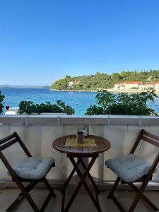 a table and two chairs on a balcony with a view of the water at Apartments Korta in Račišće