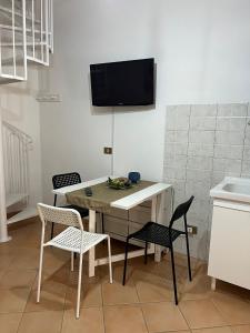 cocina con mesa y sillas y TV en la pared en La Chiocciola - Casa vacanze, en Erice