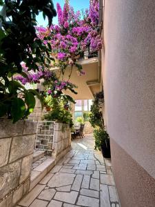a walkway with purple flowers hanging from a building at Apartments Korta in Račišće
