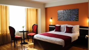 um quarto de hotel com uma cama e duas cadeiras em Hotel PLATINIUM em Tacna