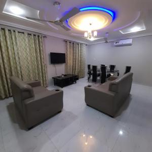 a living room with couches and a table and a tv at Atom Height Apartments in Tema