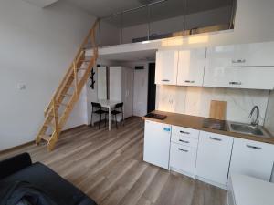 una cocina con armarios blancos, una mesa y una escalera en RestPlacePl - kawalerka - Mielczarskiego, Manufaktura en Lodz