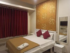 um quarto com uma cama com cortinas vermelhas e um espelho em Malwade Motel em Pune