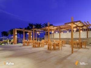 un restaurante con mesas de madera y sillas por la noche en Azha ain sokhna luxury chalet - families only - 155sqm special weekly monthly rates, en Ain Sokhna