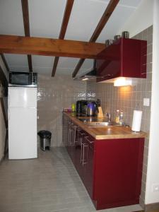 una cucina con armadi rossi e frigorifero bianco di Faubourg St Jean ad Aubeterre-sur-Dronne