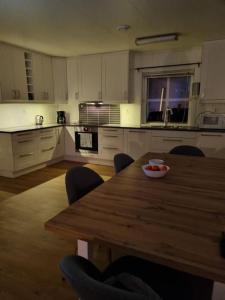 uma grande cozinha com uma mesa de madeira e cadeiras em Moderne hus med 5 soverom og 2 bad på Hidra em Hidra