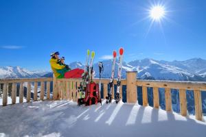 una persona está sentada en una valla con una cámara en Chalet Windegg, en Sankt Anton am Arlberg