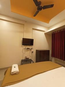 Schlafzimmer mit einem Bett und einem Deckenventilator in der Unterkunft Malwade Motel in Pune