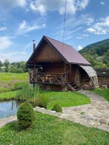 a log cabin with a pond in front of it at Садиба Краєвських in Krapivnik