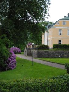a park with purple flowers and a building at Wapnö Gårdshotell in Halmstad