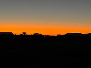 una puesta de sol en el desierto con palmeras y montañas en Nashdeen Eco Lodge, en Siwa