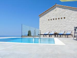 a swimming pool with lounge chairs next to a building at EMERALD AGIOS NIKITAS in Drymon