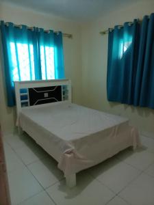 uma cama num quarto com cortinas azuis e uma janela em Casa jauá em Camaçari
