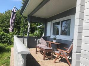 un portico con due sedie e un tavolo e un ombrellone di Ferienhaus Auszeit a Lindenfels