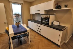 una cucina con armadi bianchi, un tavolo e una sala da pranzo di T&L-Home a Reggio di Calabria