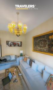 a living room with a blue couch and a chandelier at Travelers - Dubai Marina Hostel in Dubai