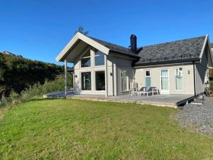 une petite maison blanche avec une terrasse couverte et une pelouse dans l'établissement Flott nyere hytte med sjøutsikt., à Risør