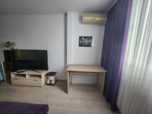 a room with a desk and a television and a table at Apartment near to airport in Sofia