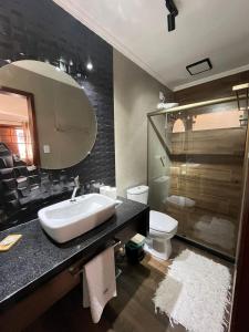 a bathroom with a sink and a toilet and a mirror at Pousada dos Sonhos - MP in Miguel Pereira