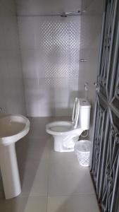 La salle de bains blanche est pourvue de toilettes et d'un lavabo. dans l'établissement Hotel Gods Time Is The Best, à Boa Vista