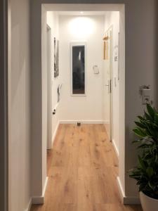 un corridoio con pareti bianche e pavimento in legno di Grüne Oase mit Balkon & Netflix I EG a Duisburg