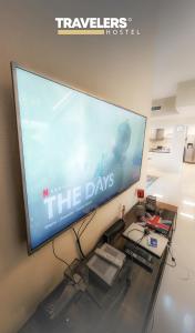 a large screen television hanging on a wall at Travelers - Dubai Marina Hostel in Dubai