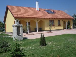 a small yellow house with a solar roof at Kiserdő Vendégház in Rajka