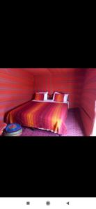 a bedroom with a bed in a red room at Erg Chebbi Starlight Camp in Merzouga