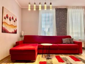 een rode bank in een woonkamer met een tafel bij Apartmánik v tichom nádvorí - free parking in Bratislava
