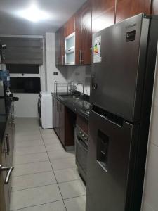 eine Küche mit einem Kühlschrank aus Edelstahl und Holzschränken in der Unterkunft frente a playa vista panorámica Departamento 3 Habitaciones 2 Baños Iquique in Iquique