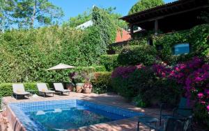 un patio trasero con una piscina con sillas y flores en CASA LAGO - LA PEÑA, en Valle de Bravo