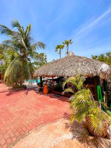 una cabaña con techo de paja y palmeras en Woodstock Palmresort Curaçao, en Willemstad