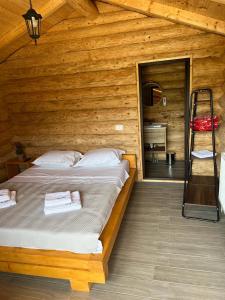una camera da letto con un letto in una cabina di legno di M&V Infinit a Sălătrucel