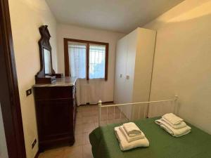 um quarto com uma cama verde e toalhas em Appartamento Immerso nel Verde em Borgo Malpasso