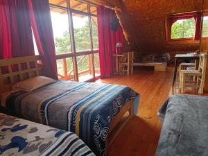 a bedroom with two beds and a large window at Treff Lodge Hotel in Oxapampa