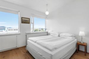 a white bedroom with a bed and a window at Nes Residence in Reykjavík