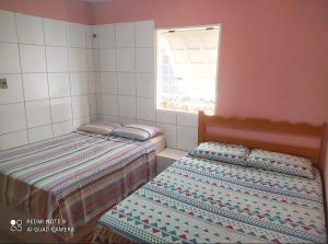 2 camas individuales en una habitación con ventana en Suítes D'Belinha, en Canoa Quebrada