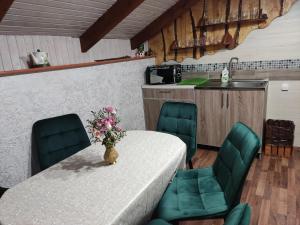 einen Tisch mit grünen Stühlen und eine Vase mit Blumen darauf in der Unterkunft Апартаменти "У Кузьмича" 1 in Mykulytschyn