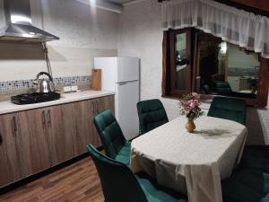 a kitchen with a table with green chairs and a refrigerator at Апартаменти "У Кузьмича" трикімнатні in Mykulychyn