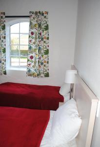 a bedroom with a red bed and a window at Wapnö Gårdshotell in Halmstad