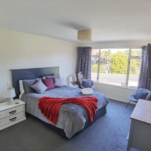 a bedroom with a bed with a red blanket and a window at Kea by the Lake in Te Anau