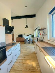 a large kitchen with white cabinets and a wooden floor at Ferienwohnung Waldliebe in Homburg