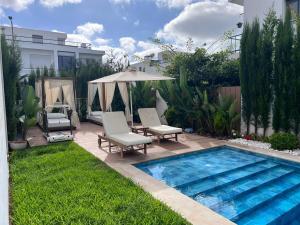 a backyard with a swimming pool with chairs and an umbrella at Tamares in Casablanca