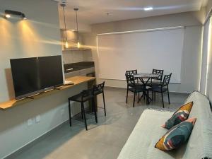 sala de estar con TV, mesa y sillas en Apartamento aconchegante no centro de São Lourenço en São Lourenço