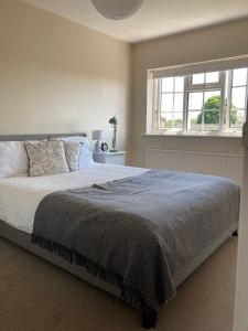 a bedroom with a large bed and a window at Pristine 3 Bed Home For Family or Business Stays, Great Location, FREE Parking, Park Views, Sleeps 5! in Ashford