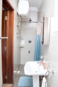 a white bathroom with a sink and a shower at Luxor garden apartments Accra Ghana in Accra