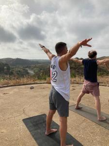 two men standing on a mat with their arms in the air at Yoga Farm in Tavira