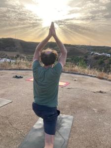 Yoga Farm في تافيرا: رجل واقف على صخرة ويده في الهواء