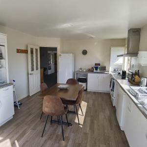 a kitchen with white cabinets and a wooden table and chairs at Kea by the Lake in Te Anau